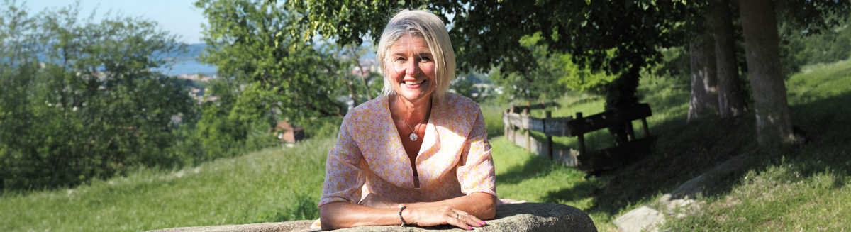 Tatjana von Lebe leichter Freiburg in der Natur aufgestützt auf einem Stein lächelnd in die Kamera