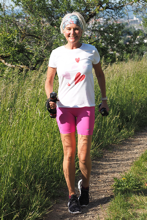 Tatjana in der Natur mit Sportkleidung und zwei kleine Hanteln